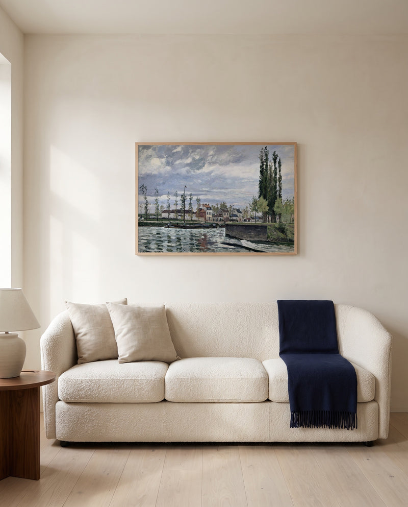 The Lock at Pontoise by Camille Pissarro framed in natural oak above a cream sofa in a warm living room
