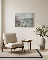 The Louvre, Rainy Weather by Camille Pissarro as a stretched canvas above a linen lounge chair in a reading corner