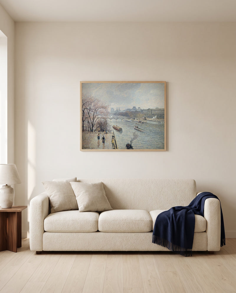 The Louvre, Rainy Weather by Camille Pissarro framed in natural oak above a cream sofa in a warm living room