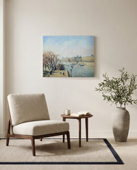 The Louvre, Morning by Camille Pissarro as a stretched canvas above a linen lounge chair in a reading corner