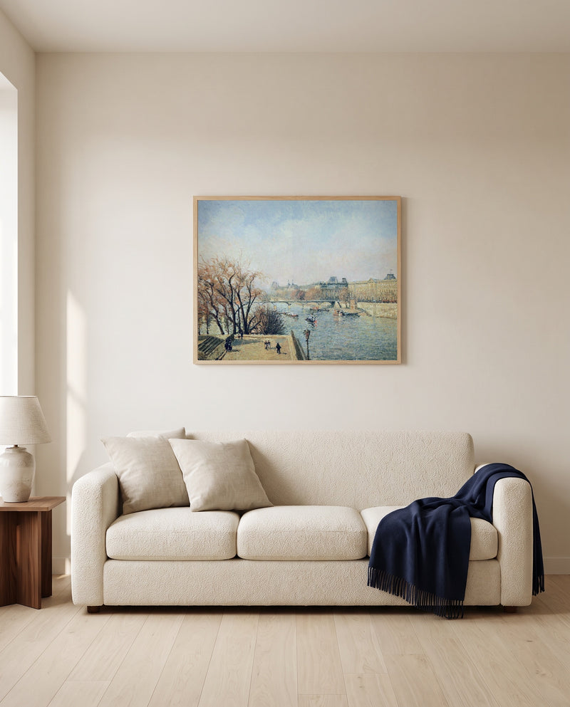 The Louvre, Morning by Camille Pissarro framed in natural oak above a cream sofa in a warm living room