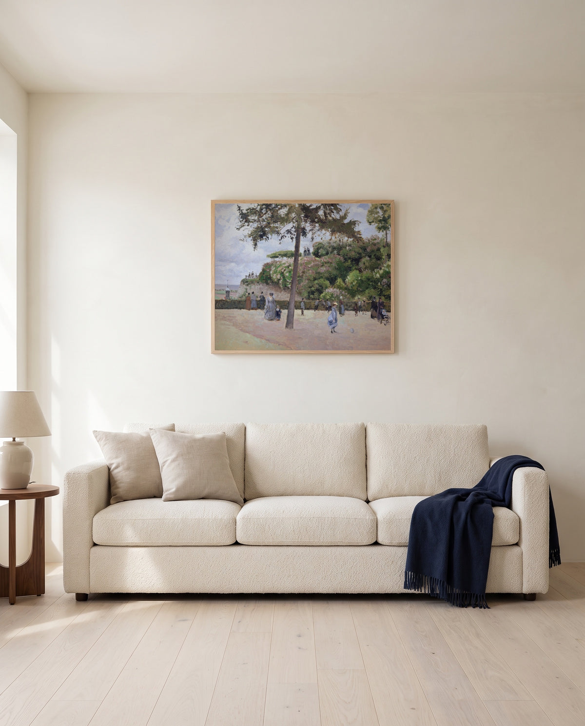 Public Garden, Pontoise by Camille Pissarro framed in natural oak above a cream sofa in a warm living room
