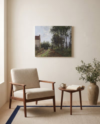 The Road Near the Farm by Camille Pissarro as a stretched canvas above a linen lounge chair in a reading corner