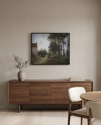 The Road Near the Farm by Camille Pissarro in a black frame above a walnut sideboard in a dining room