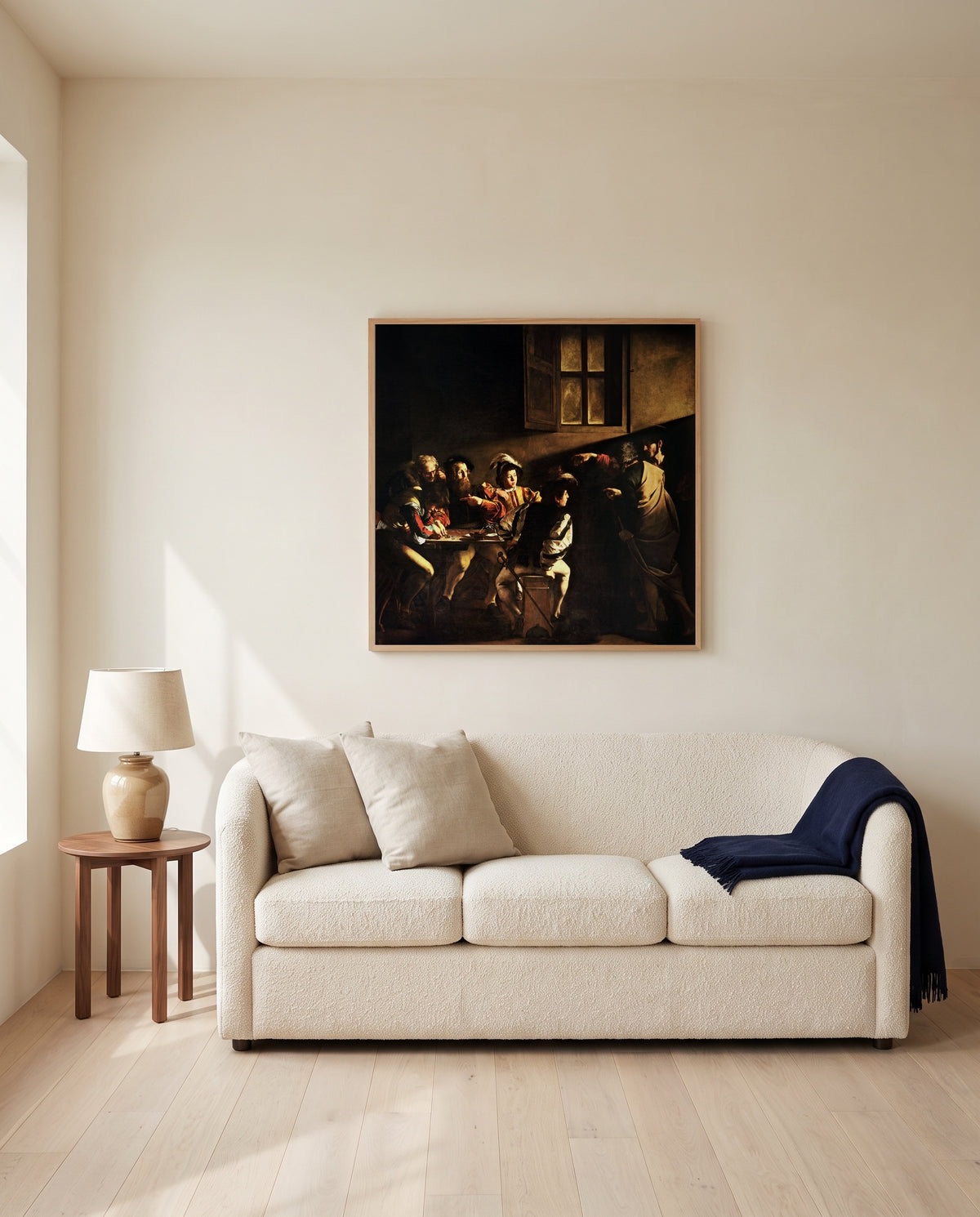 The Calling of Saint Matthew by Caravaggio framed in natural oak above a cream sofa in a warm living room