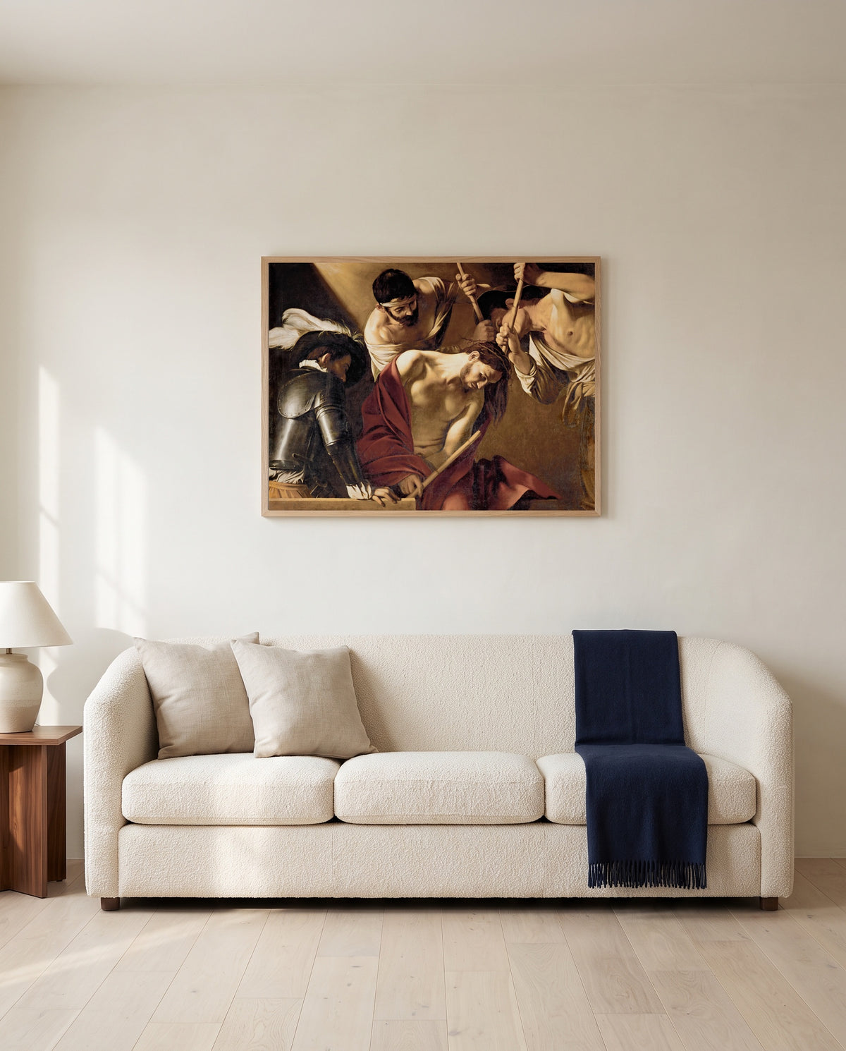 The Crowning with Thorns by Caravaggio framed in natural oak above a cream sofa in a warm living room