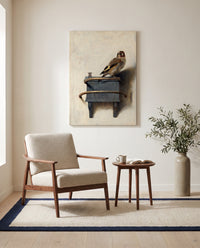 The Goldfinch by Carel Fabritius as a stretched canvas above a linen lounge chair in a reading corner