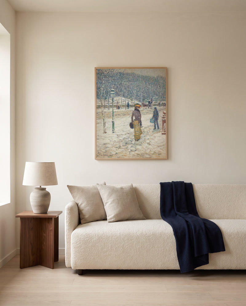 New York Street by Childe Hassam framed in natural oak above a cream sofa in a warm living room