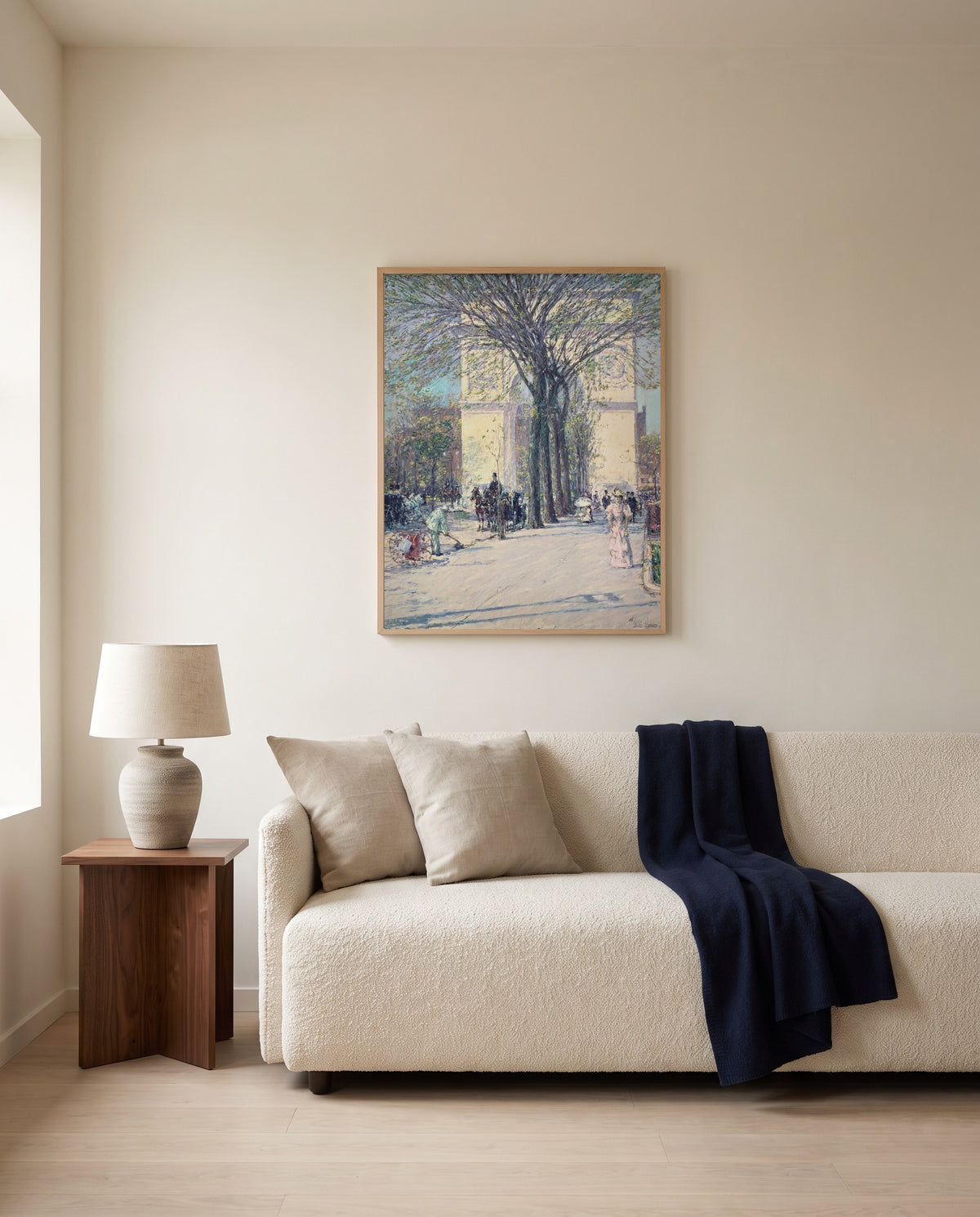 Washington Arch, Spring by Childe Hassam framed in natural oak above a cream sofa in a warm living room