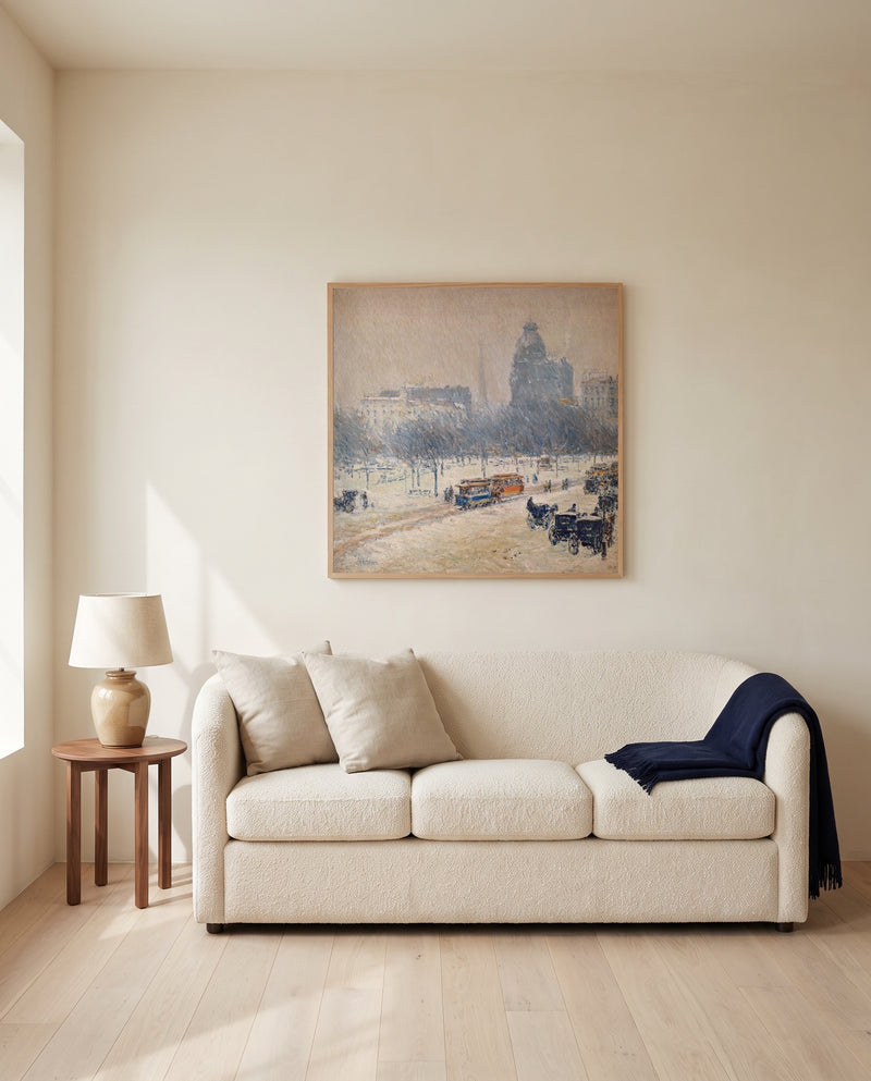 Winter in Union Square by Childe Hassam framed in natural oak above a cream sofa in a warm living room