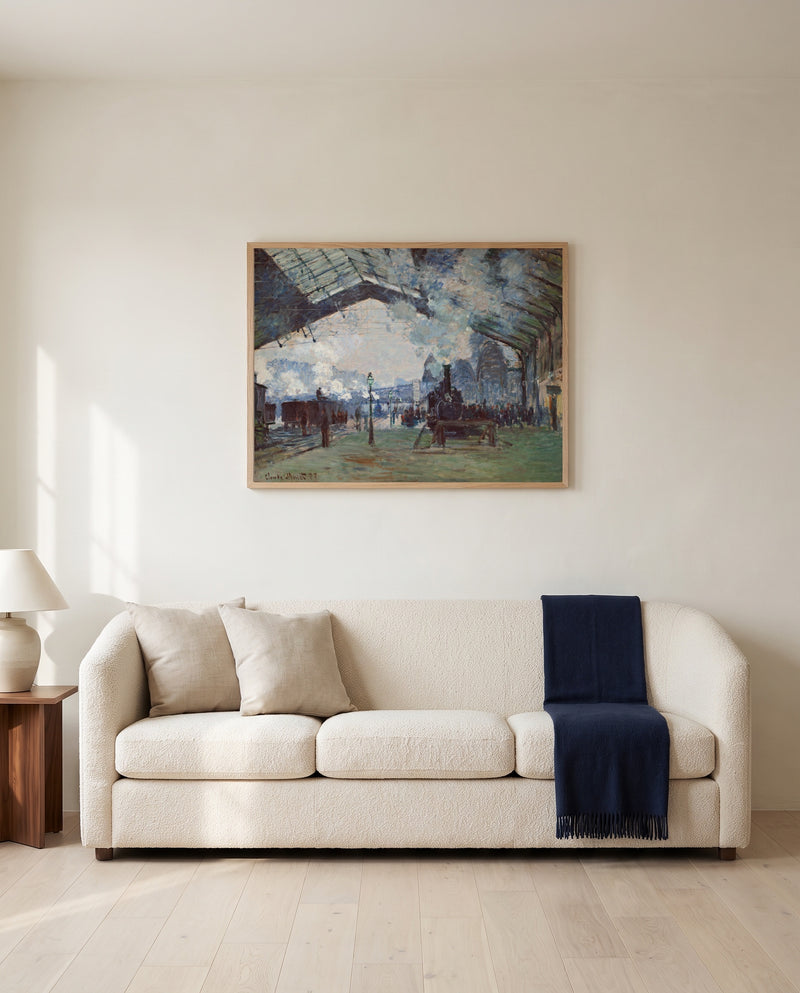 Arrival of the Normandy Train by Claude Monet framed in natural oak above a cream sofa in a warm living room