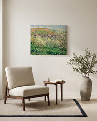 Plum Trees in Blossom by Claude Monet as a stretched canvas above a linen lounge chair in a reading corner
