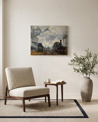 Gare Saint-Lazare by Claude Monet as a stretched canvas above a linen lounge chair in a reading corner