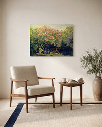 Lilac Bush in the Sun by Claude Monet as a stretched canvas above a linen lounge chair in a reading corner