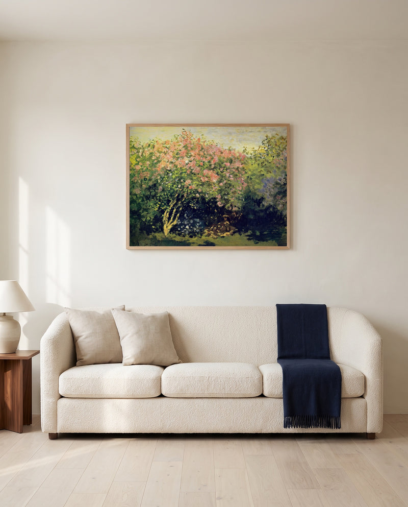 Lilac Bush in the Sun by Claude Monet framed in natural oak above a cream sofa in a warm living room