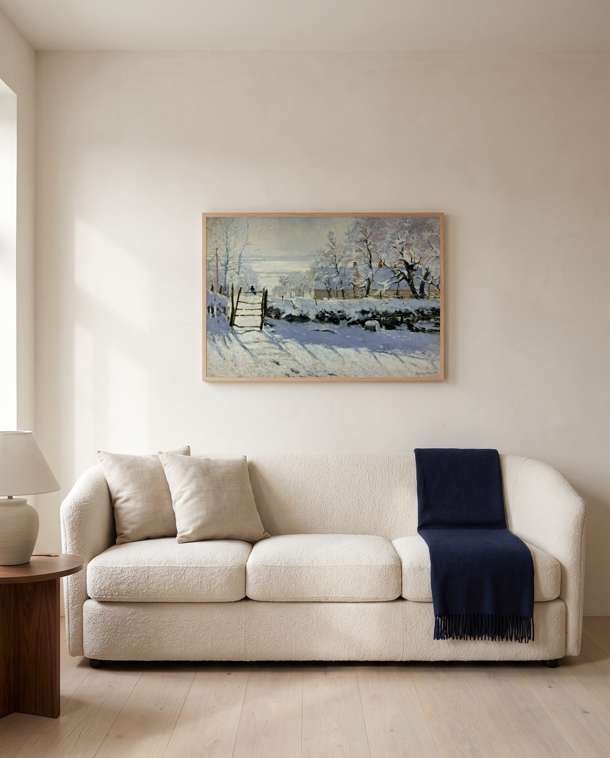 The Magpie by Claude Monet framed in natural oak above a cream sofa in a warm living room