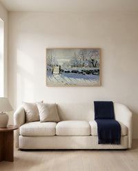 The Magpie by Claude Monet framed in natural oak above a cream sofa in a warm living room