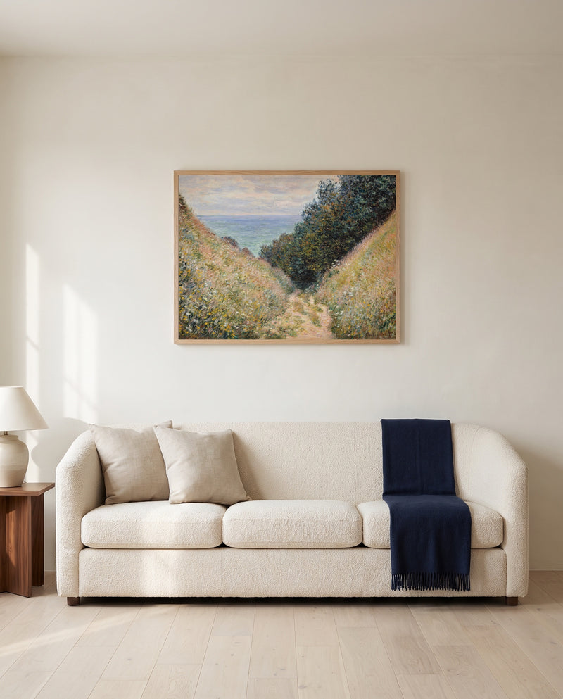 Road at La Cavée by Claude Monet framed in natural oak above a cream sofa in a warm living room