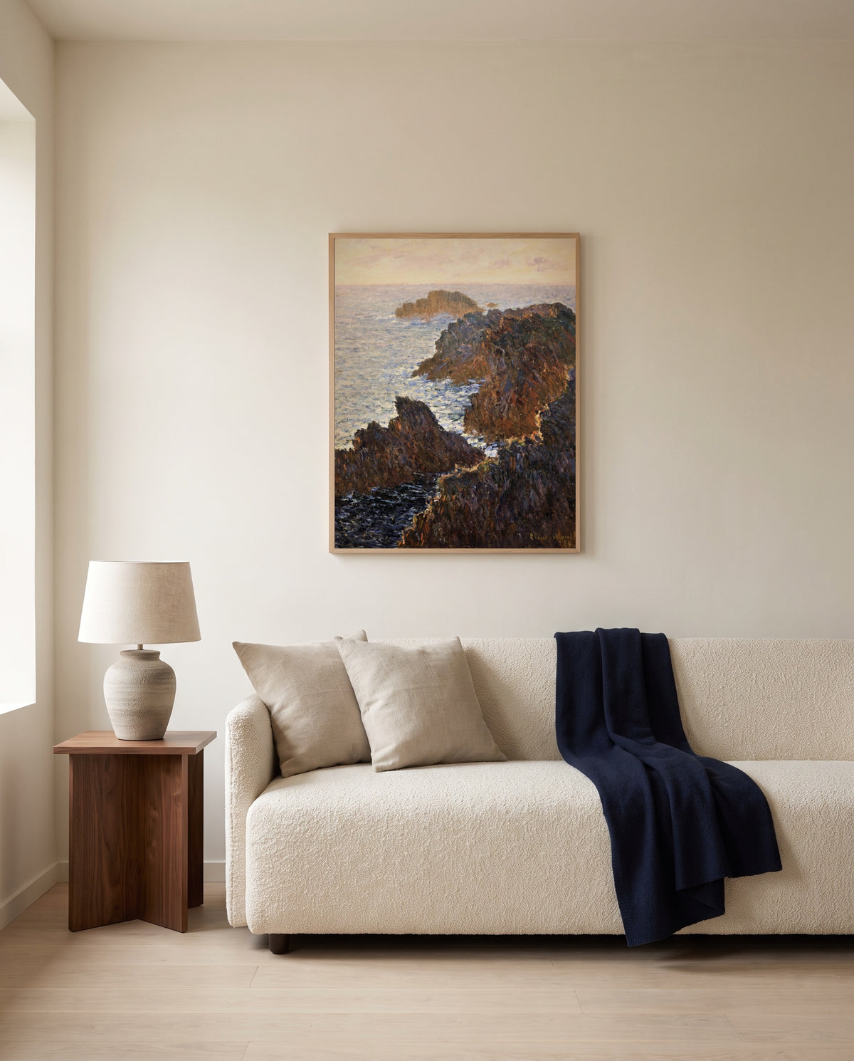 Rocks at Belle-Isle by Claude Monet framed in natural oak above a cream sofa in a warm living room