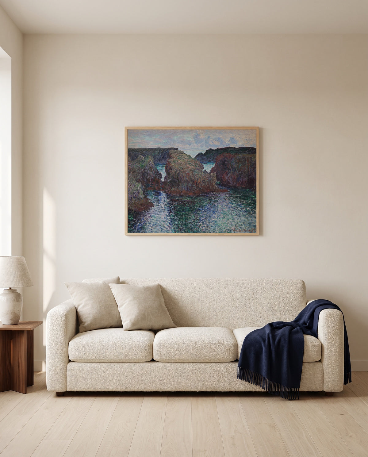 Rocks at Port-Goulphar, Belle-Île by Claude Monet framed in natural oak above a cream sofa in a warm living room