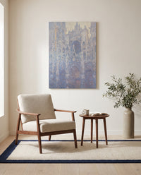 Rouen Cathedral, Morning by Claude Monet as a stretched canvas above a linen lounge chair in a reading corner