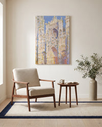 Rouen Cathedral, Sunlight by Claude Monet as a stretched canvas above a linen lounge chair in a reading corner