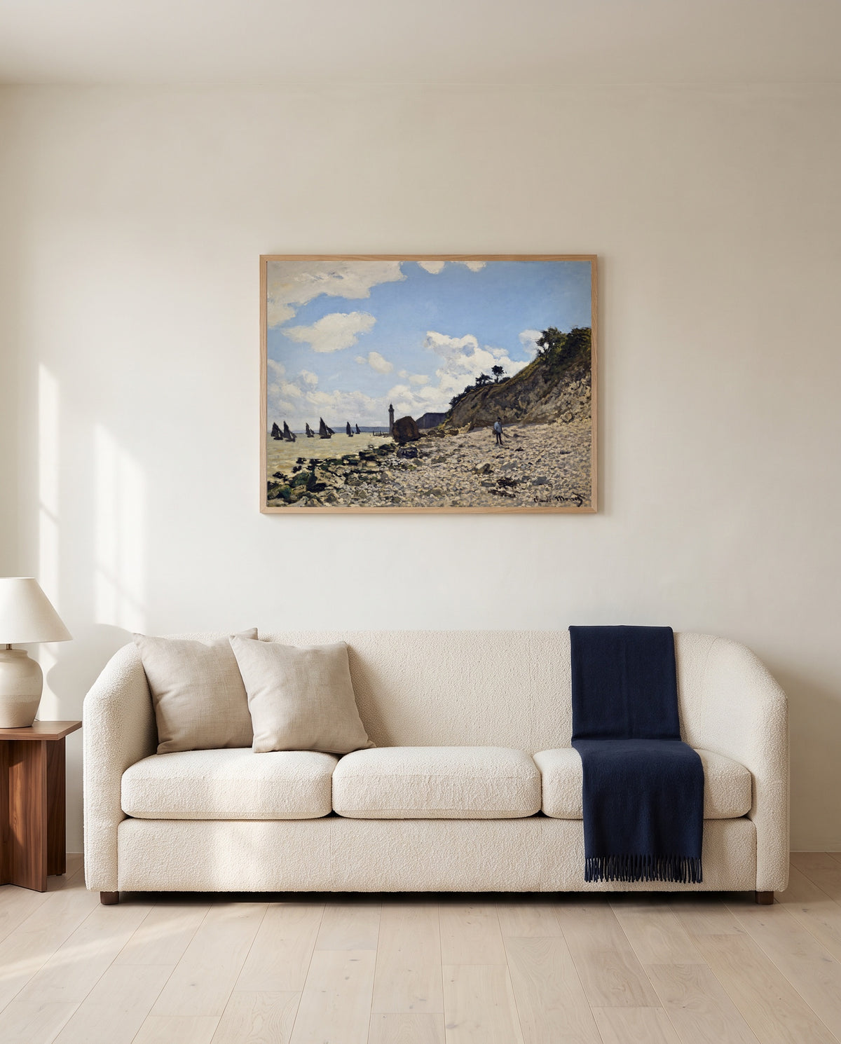 The Beach at Honfleur by Claude Monet framed in natural oak above a cream sofa in a warm living room