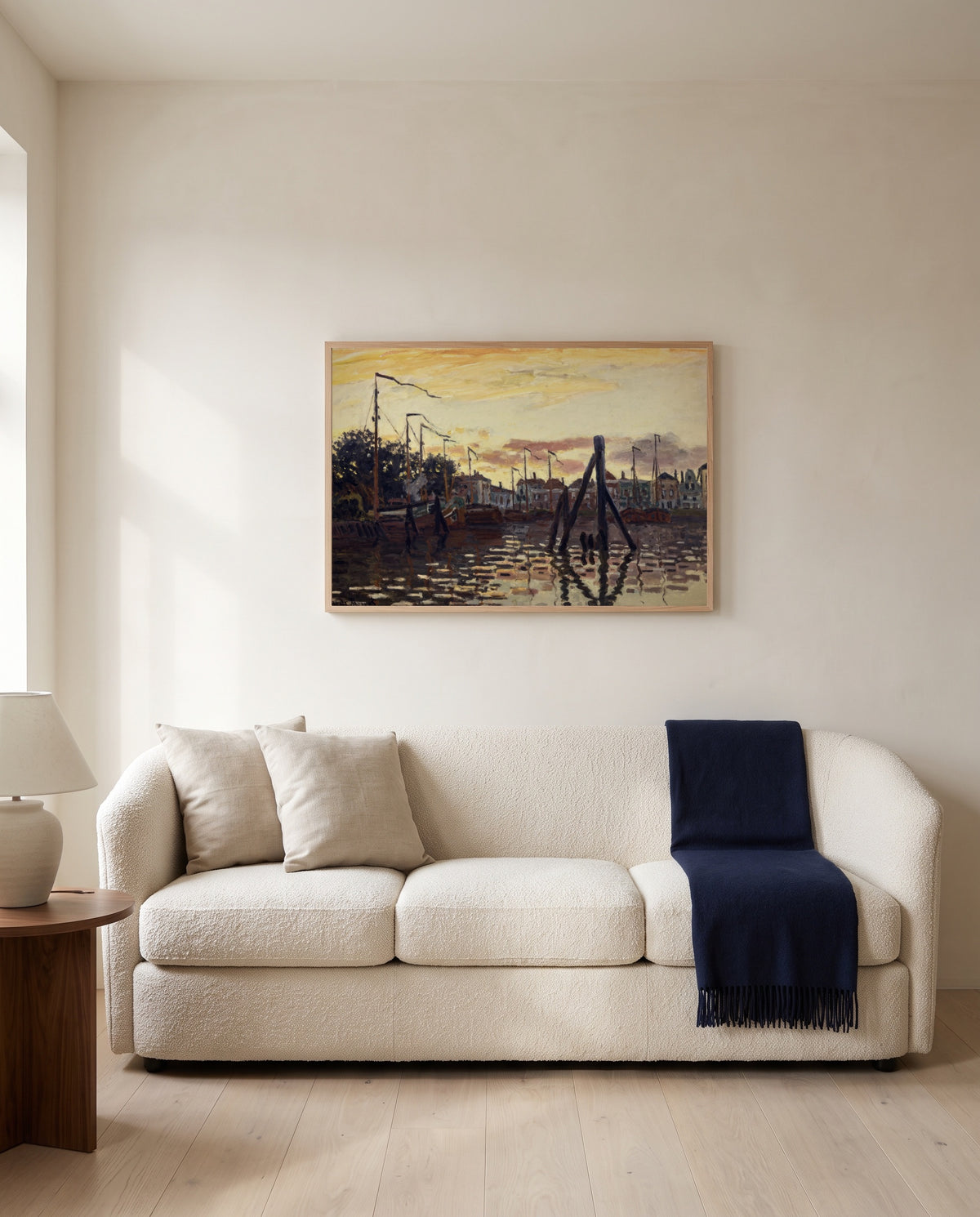 The Port of Zaandam by Claude Monet framed in natural oak above a cream sofa in a warm living room
