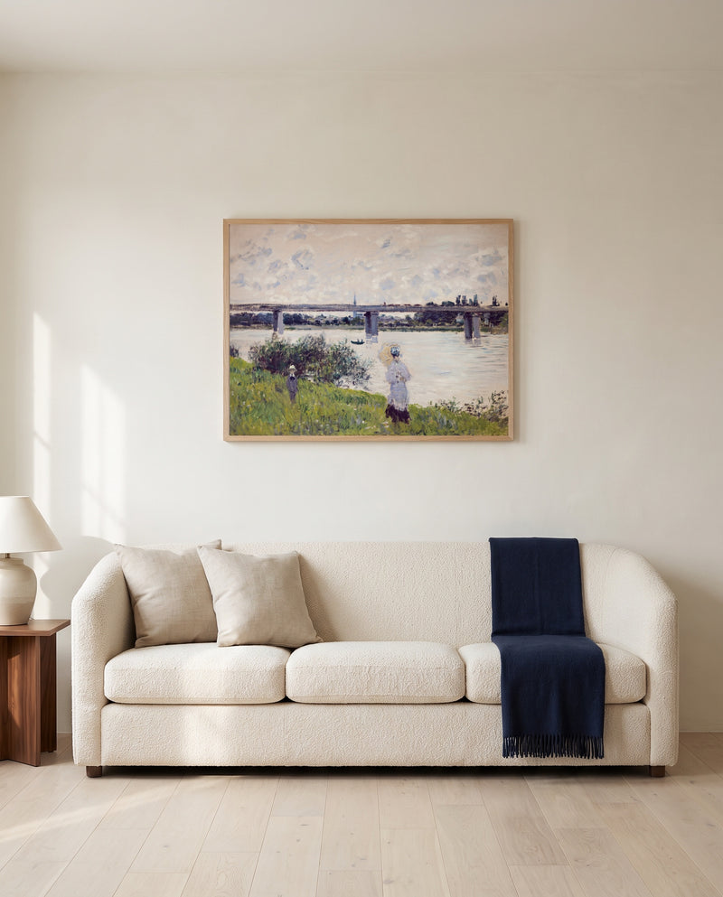 Promenade, Railroad Bridge by Claude Monet framed in natural oak above a cream sofa in a warm living room