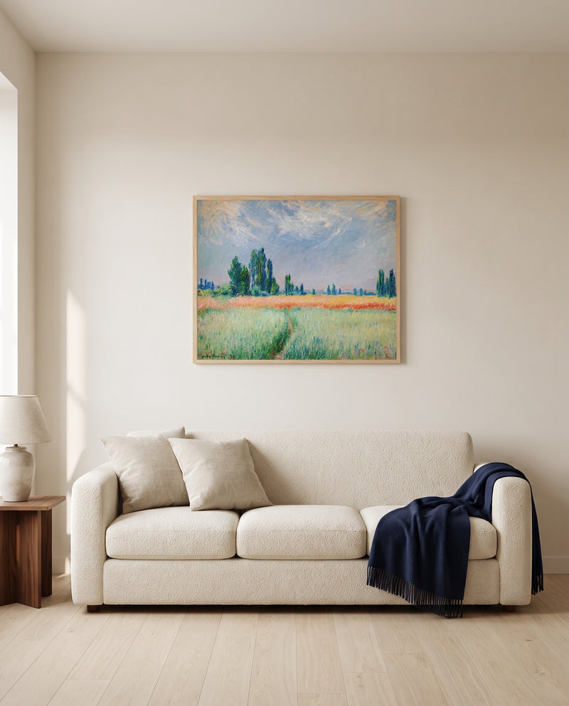 Wheatfield by Claude Monet framed in natural oak above a cream sofa in a warm living room