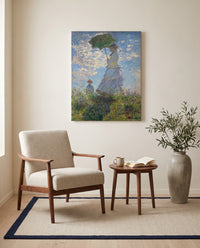 Woman with a Parasol by Claude Monet as a stretched canvas above a linen lounge chair in a reading corner