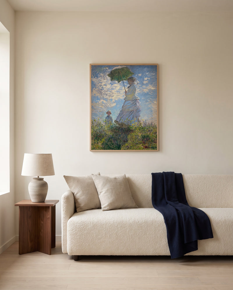 Woman with a Parasol by Claude Monet framed in natural oak above a cream sofa in a warm living room