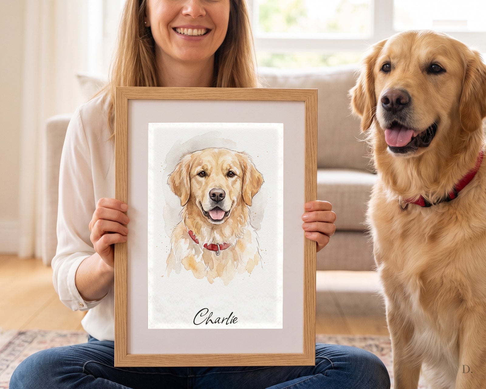 Owner holding a framed watercolor portrait beside the golden retriever it was painted from