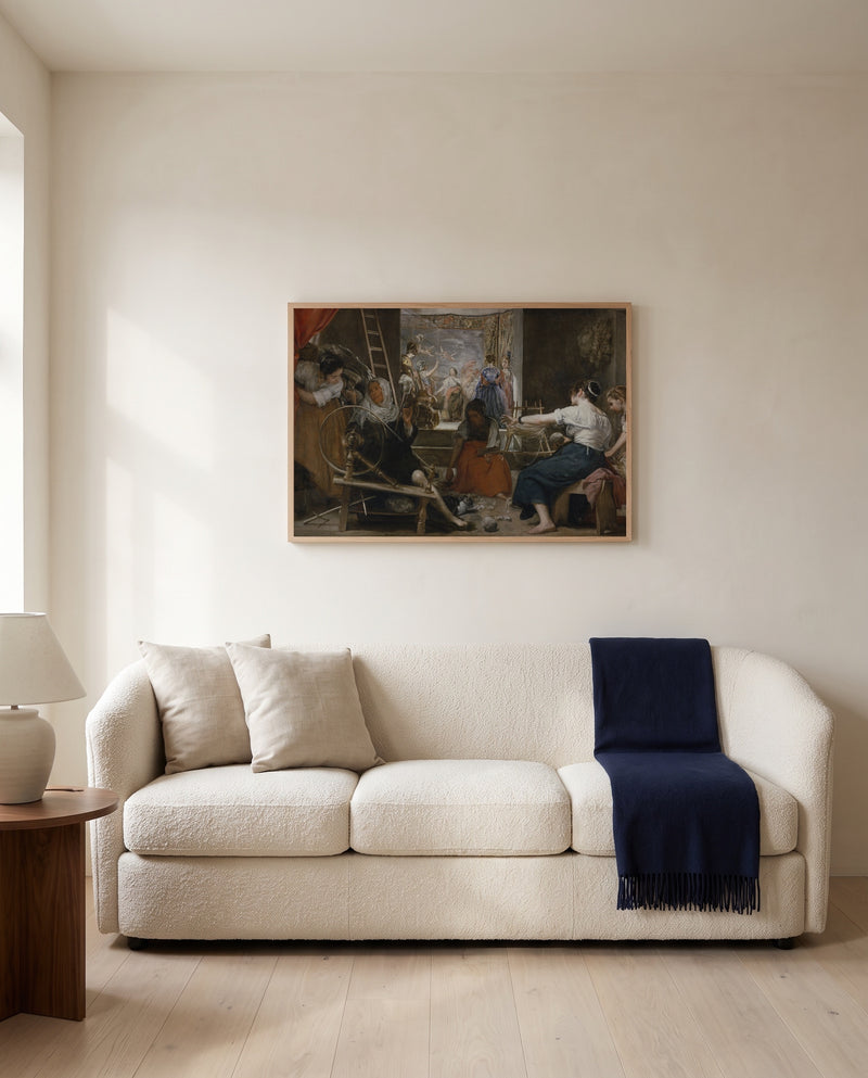 Las Hilanderas by Diego Velázquez framed in natural oak above a cream sofa in a warm living room