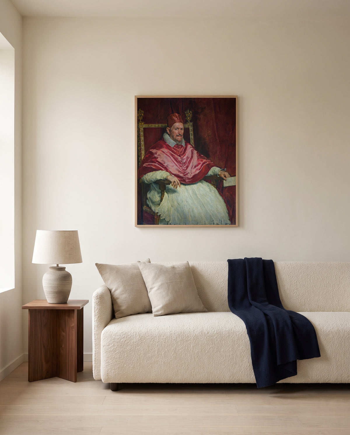 Pope Innocent X by Diego Velázquez framed in natural oak above a cream sofa in a warm living room
