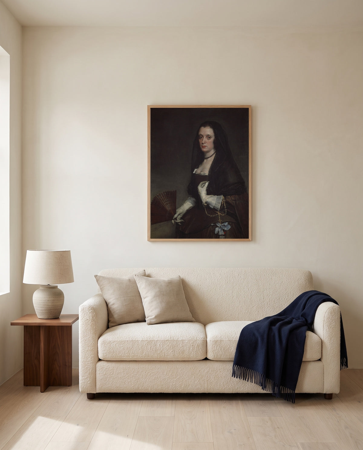 The Lady with a Fan by Diego Velázquez framed in natural oak above a cream sofa in a warm living room