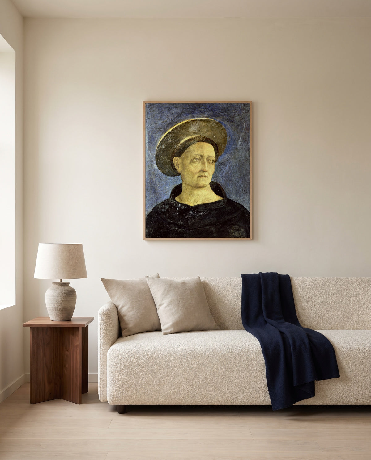 Head of a Beardless Saint by Domenico Veneziano framed in natural oak above a cream sofa in a warm living room