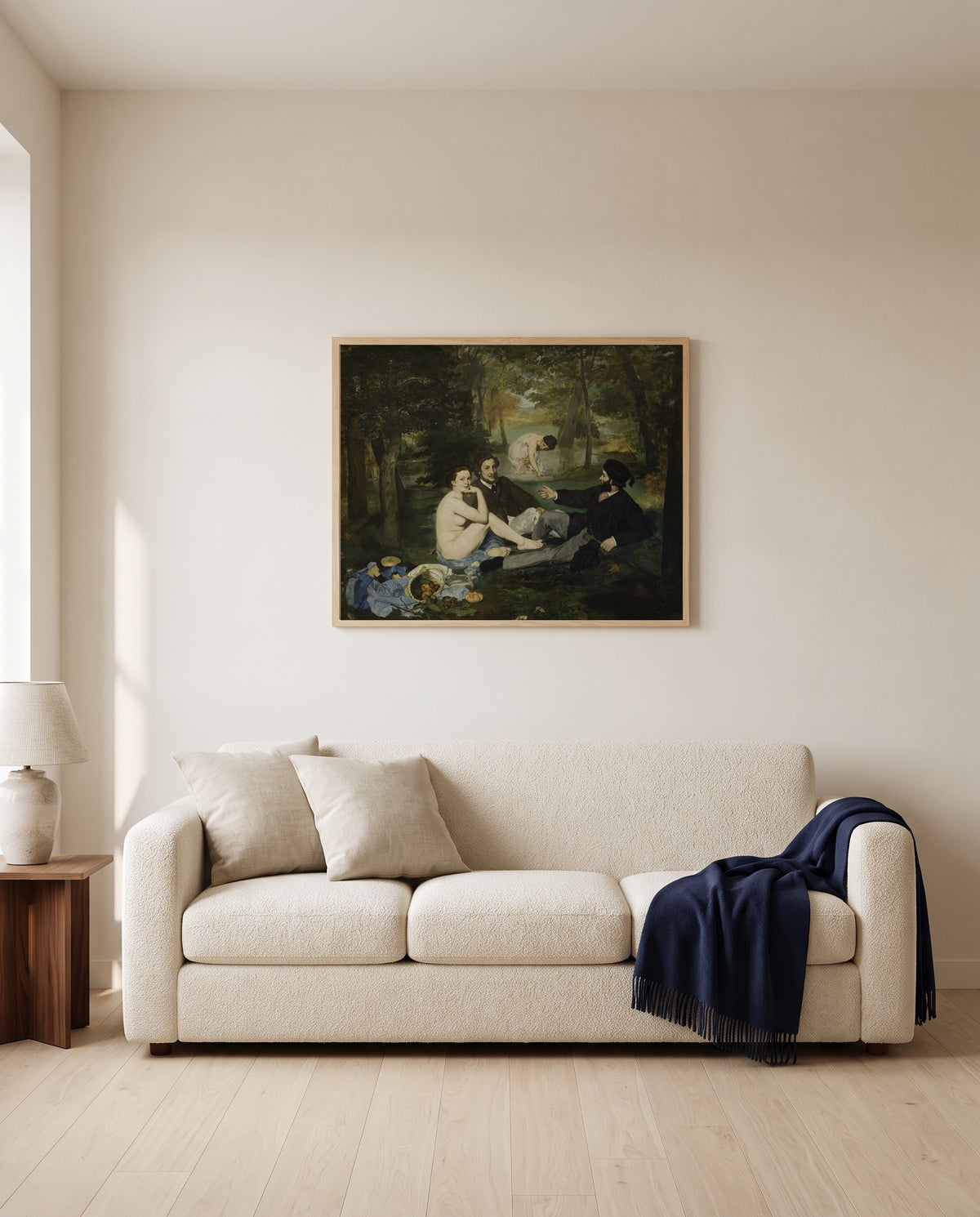 Le Déjeuner sur l’herbe by Édouard Manet framed in natural oak above a cream sofa in a warm living room
