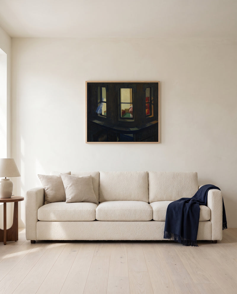 Night Windows by Edward Hopper framed in natural oak above a cream sofa in a warm living room