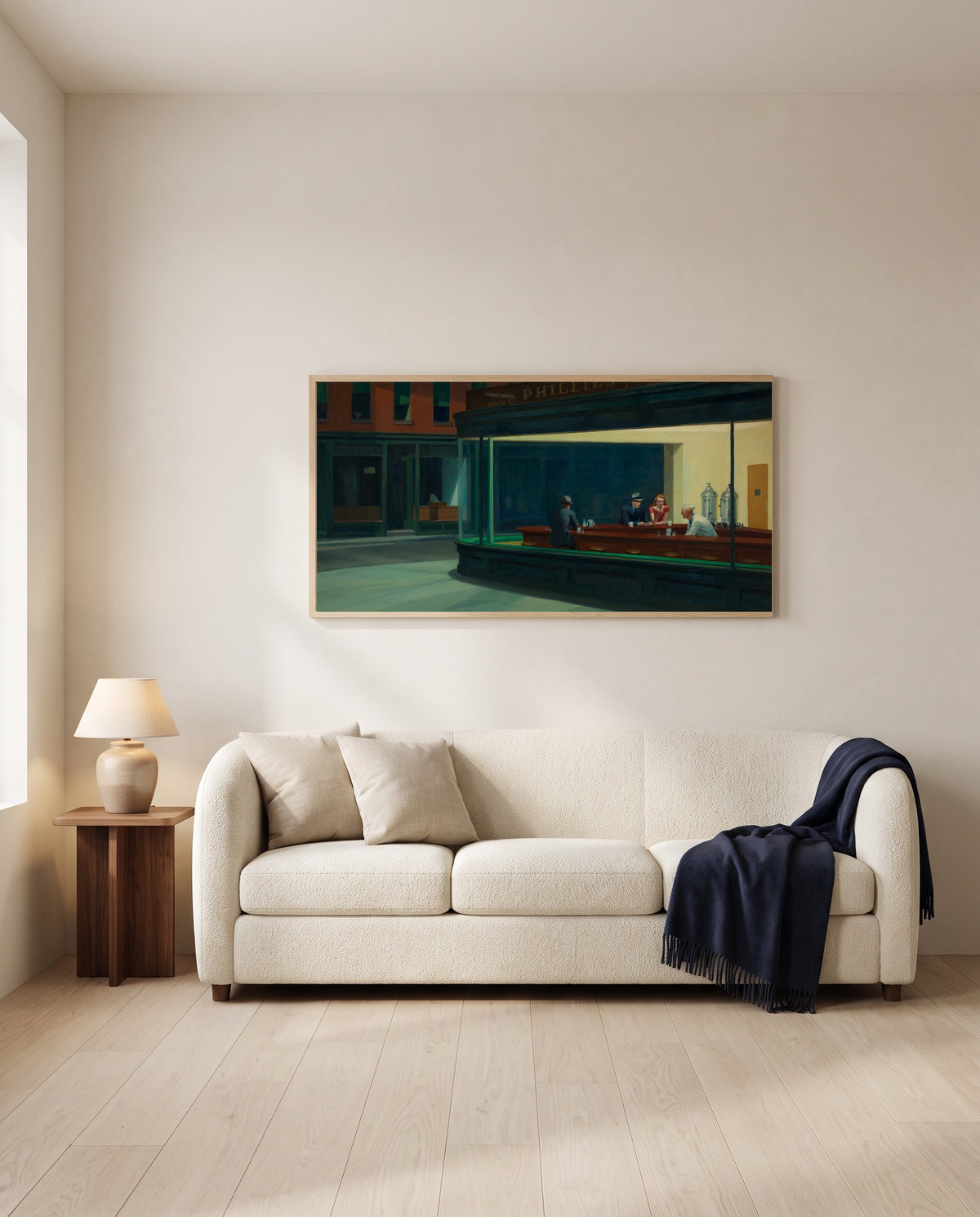Nighthawks by Edward Hopper framed in natural oak above a cream sofa in a warm living room