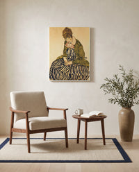 Edith in a Striped Dress (Vienna) by Egon Schiele as a stretched canvas above a linen lounge chair in a reading corner