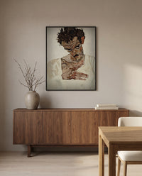 Self-Portrait, Lowered Head by Egon Schiele in a black frame above a walnut sideboard in a dining room