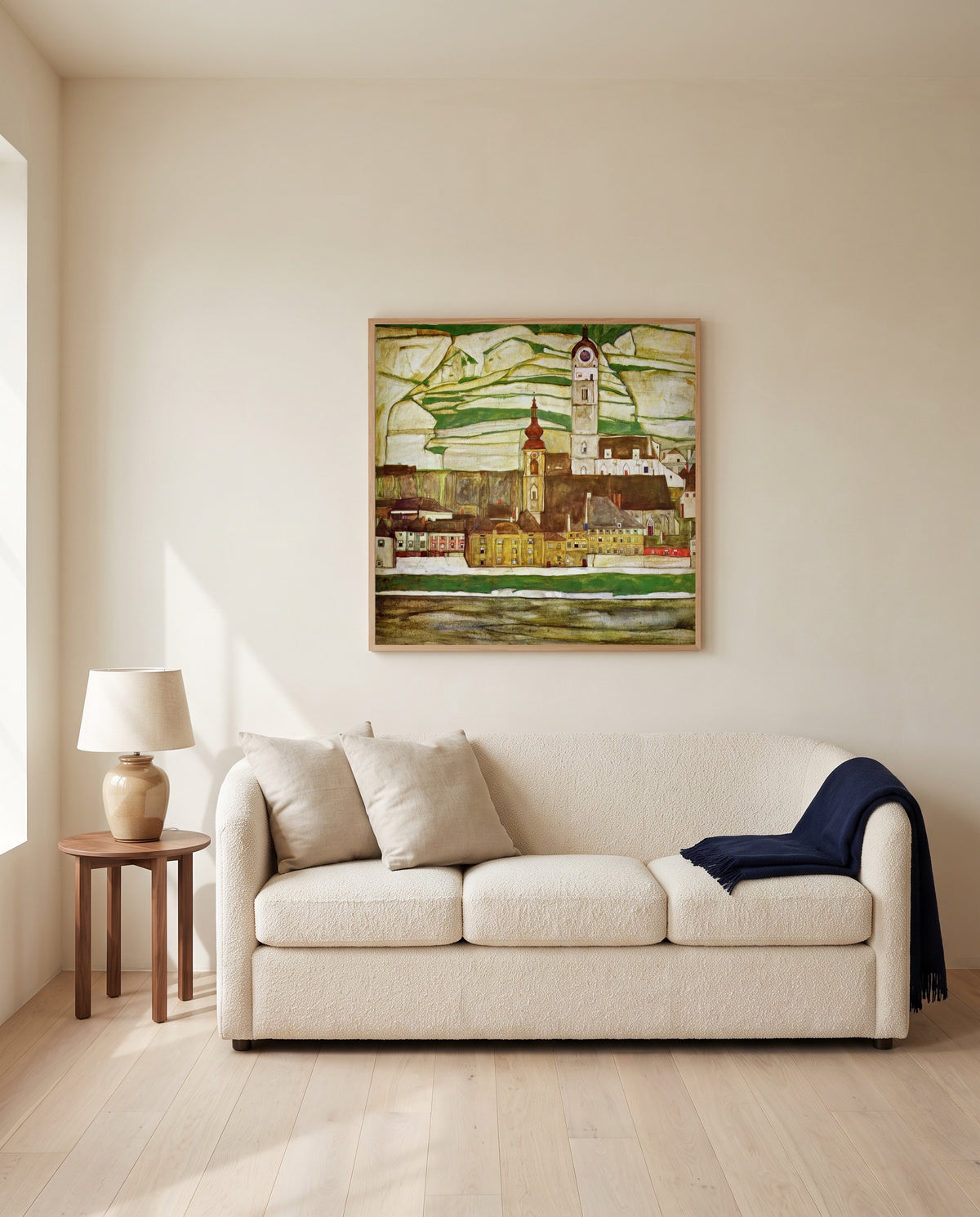 Stein on the Danube by Egon Schiele framed in natural oak above a cream sofa in a warm living room