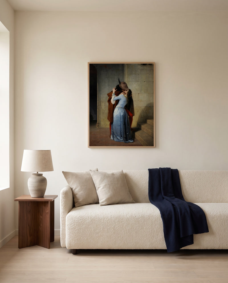 The Kiss by Francesco Hayez framed in natural oak above a cream sofa in a warm living room