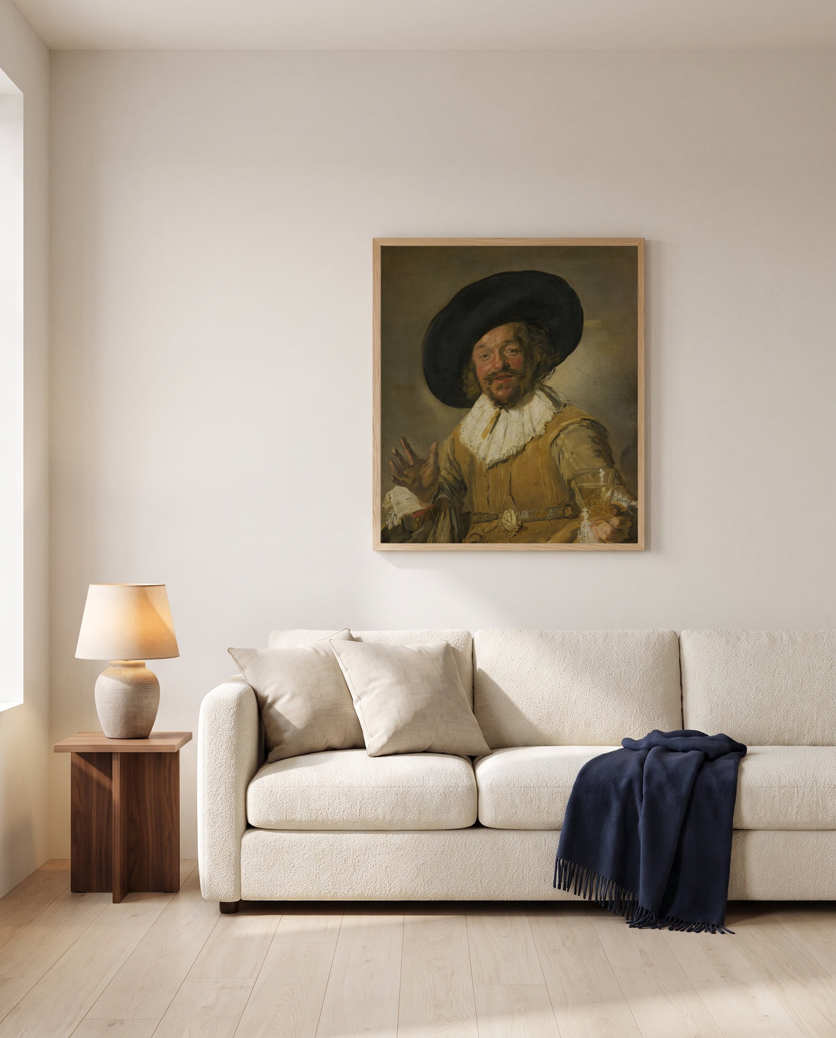 The Merry Drinker by Frans Hals framed in natural oak above a cream sofa in a warm living room