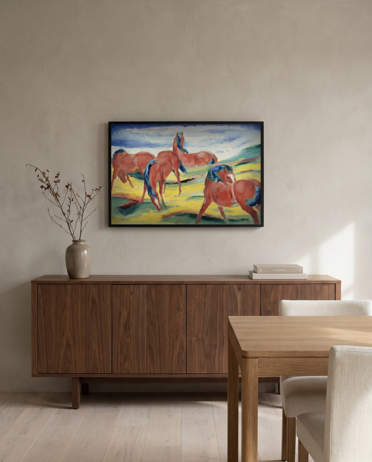 Grazing Horses III by Franz Marc in a black frame above a walnut sideboard in a dining room