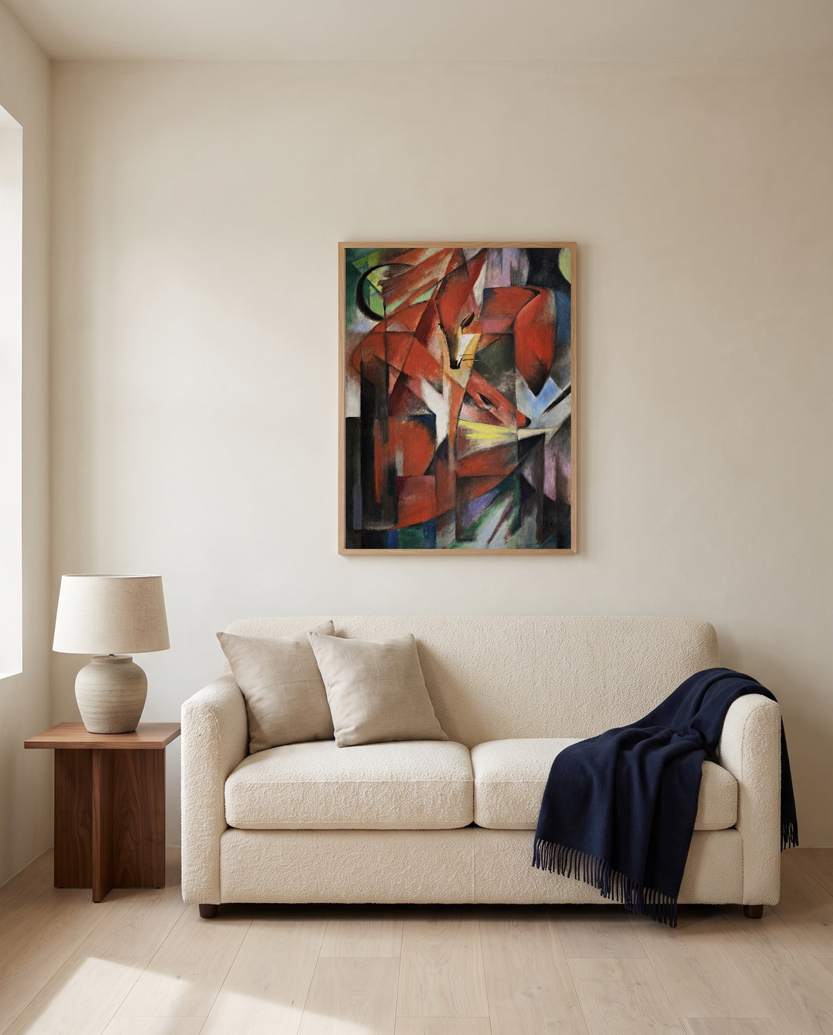 The Foxes by Franz Marc framed in natural oak above a cream sofa in a warm living room