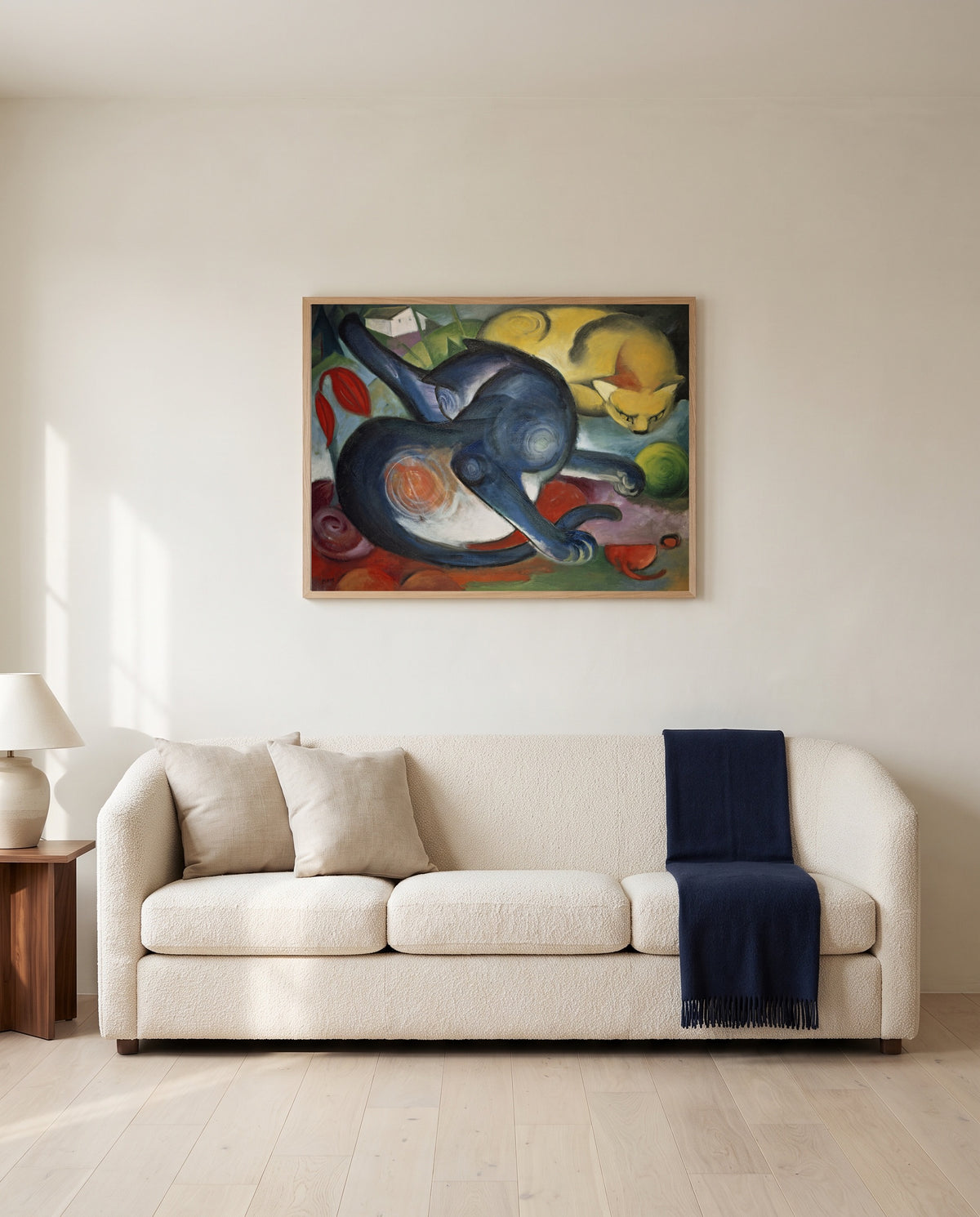Two Cats, Blue and Yellow by Franz Marc framed in natural oak above a cream sofa in a warm living room