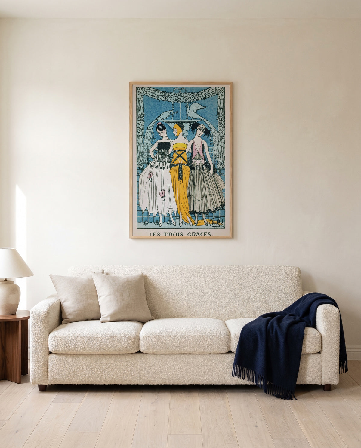 Les Trois Grâces by George Barbier framed in natural oak above a cream sofa in a warm living room
