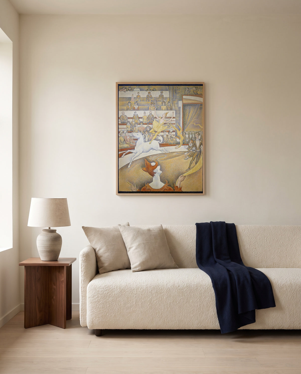 The Circus by Georges Seurat framed in natural oak above a cream sofa in a warm living room
